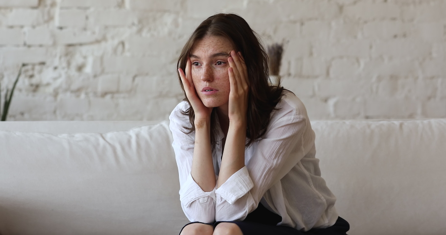 Worried young woman having psychological problem, feeling anxiety looks stressed, nervous sit on sofa deep in sad thoughts experiences break up, make decision, thinks of personal life concerns concept | Shutterstock HD Video #1083762382