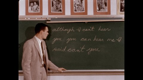 1950s: Slate. Teacher lifts a map of the Mediterranean to reveal a sentence without punctuation on the chalkboard. He talks. Slate. Teacher shows a story to the class.