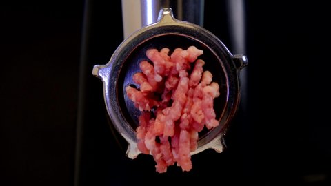 Minced meat cooking process. Household meat grinder front view. 4K footage with dark background