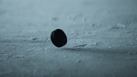 CU View of a hockey puck falling on ice in slow motion. Shot with 2x anamorphic lens