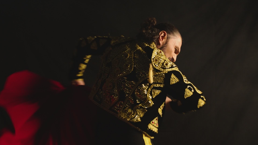 Male dancer or toreador imitating moves of matador bullfighter on black smoky background .  Man bullfighter dressed in bullfighting costume . Shot on ARRI Alexa cinema camera in Slow Motion 