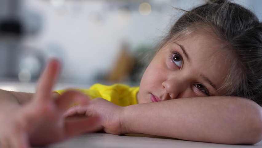 Sad girl at the table in room. Unhappy face of girl. Teenager sits at table. Preschooler child crying while sitting at table in room. Sad lazy kid. Preschool education concept. Man loneliness at home Royalty-Free Stock Footage #1083772897