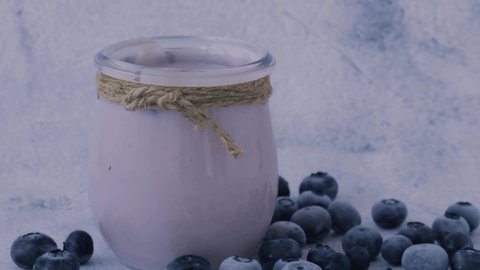 Blueberry smoothie topped with blueberries. Woman eating from glass of breakfast protein smoothie drink made from pureed raw blueberries, banana, milk, yogurt, and cottage cheese.