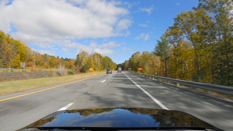 Driving a car on asphalt highway road in Vermont. Multi color trees in fall season. Sunny day with blue sky