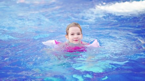time-lapse. a funny little girl swims in inflatable armbands in a pool. safety of children on the water. inflatable toys for swimming and playing in the water. swimming training.