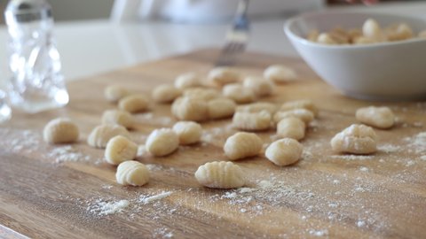 Focus on Homemade Gnocchi With Woman Making Gnocchi in the Background