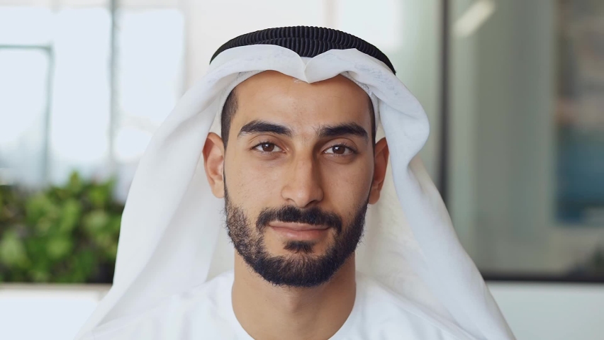 Handsome man with dish dasha working in his business office of Dubai. Portraits of a successful businessman in traditional emirates white dress. Concept about middle eastern cultures | Shutterstock HD Video #1083797323