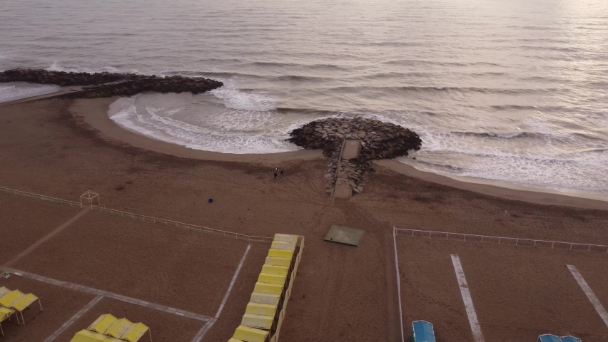 Aerial Orbit shot of People Walking on sandy beach of Mar del Plata during sunrise - Argentina,South America