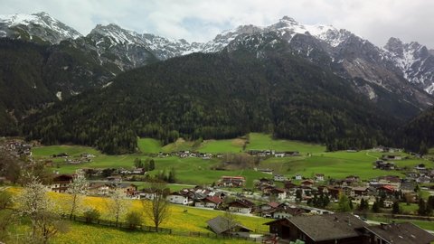 Landscape of Neustift in Stubai Valley with a meadow, cherry and dandelion blossoms and a farm