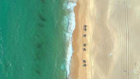 Overhead view of horse expedition in the beach with people riding, above top down aerial, Melides Portugal