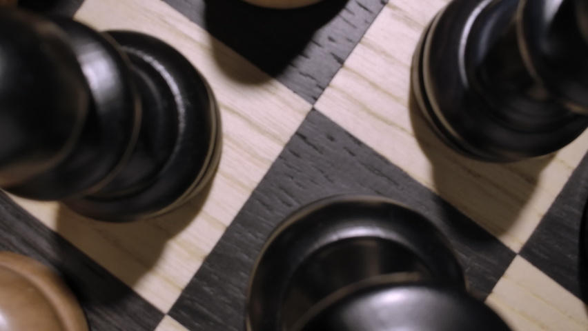 rotating chessboard with combination of white and black wooden chess figures . Top view. Camera moves from the macro to the top view. High quality 4k footage Royalty-Free Stock Footage #1083810142