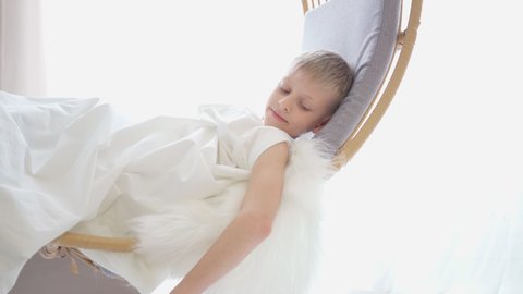 Cupid with white wings and an arrow with a red heart. Valentine's day child dressed as an angel with wings. 4k video in a white studio. Congratulations on Valentines Day. Boy waving his heart