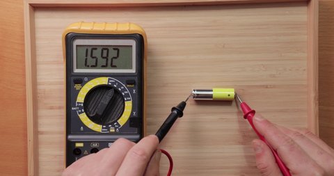 Testing AA battery cell with digital multimeter tool, voltage check showing good value, battery is still new and full charge, thumbs up