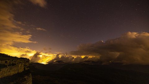 A timelapse at night of the clouds in the mountains with a storm in the distance