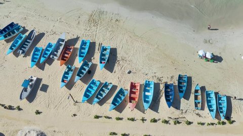 Fishing boats from above resemble blinds. Blue and orange boats look especially beautiful on the white sandy beach. The boats will be sailing soon.