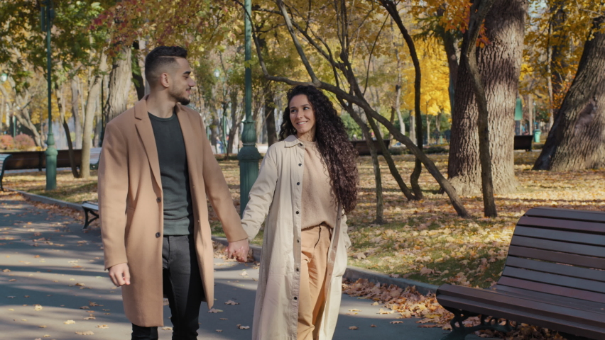 Young positive arabic couple walking holding hands date in autumn city park attractive girl happily whirling handsome bearded guy hugging girlfriend outdoors man and woman enjoying spend time together Royalty-Free Stock Footage #1083825376