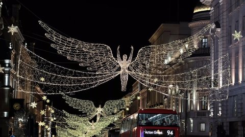 LONDON, UK – November 13, 2021: London bus with masked occupants drives past Christmas Light Angels on Regent Street, London, England, UK