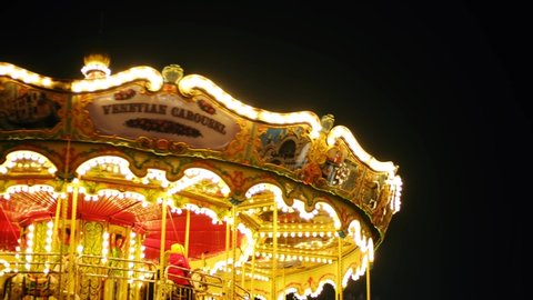 Illuminated merry go round carousel filmed at night in amusement park.KYIV-13 DECEMBER,2021 
