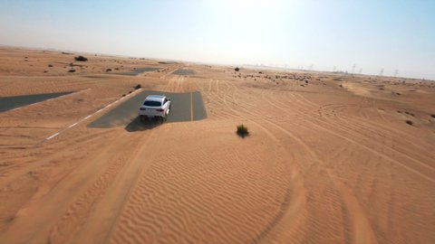 Dubai , United Arab Emirates - 12 03 2021: Dubai’s half desert road with a white Mercedes GLE63 AMG - FPV drone shot