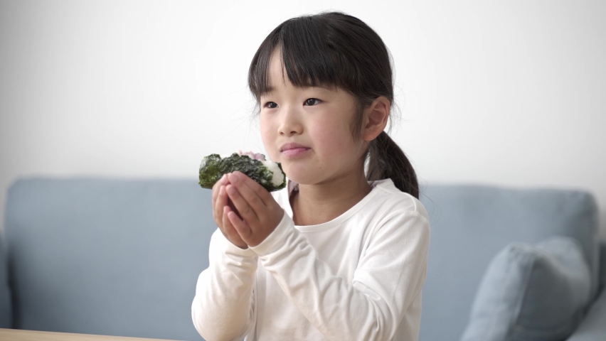 young asian girl eating rice ball