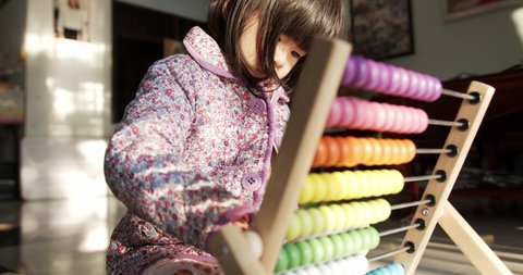 Close up, Little girl playing with colorful abacus in the house. In the morning with the soft sunlight.