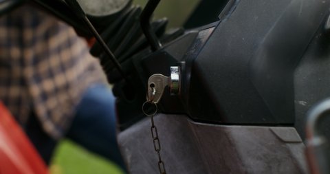 A man gets into an agricultural tractor and turns the key in the ignition, close-up of the key, the man's face is not visible