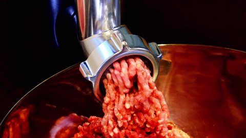 Minced meat cooking process. Household meat grinder side view. 4K footage with dark background