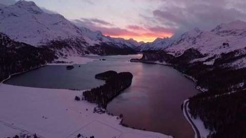 Dramatic sunset over the Sils Segl Maria village by the Silsersee lake in winter in the Engadine valley in Canton Graubunden in the Swiss alps. Shot with a revealing tilt up motion