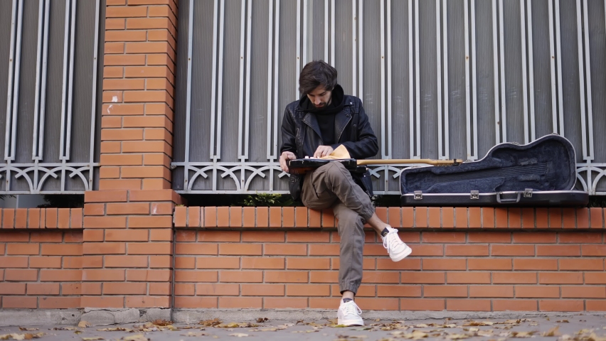 Man take care of the guitar sitting on the street