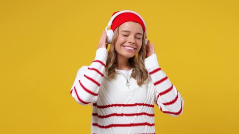 Vivid cheerful cute young girl teen student wears striped white shirt hat listen music in headphones dance have fun gesticulating hands enjoy relax isolated on plain yellow background studio portrait