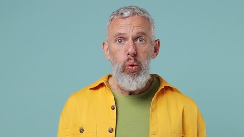 Close up shocked surprised stupefied elderly gray-haired bearded man 50s wears yellow shirt look camera surprised ask what wow omg no way isolated on plain pastel light blue background studio portrait