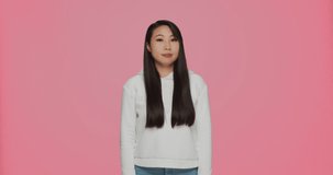 Disappointed young asian girl show thumbs down, dislike of bad service, say no and refuse on pink studio background