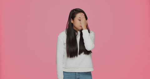 Asian young girl make gesture facepalm feel disappointment or shame because of mistake, failure on pink background