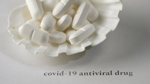 Closeup shot of pills on a seashell with white background. Black text. Virus prevention and treatment concept. Worldwide pandemic. Camera slowly moving diagonally. Selective focus.