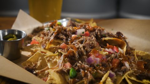 Nachos piled high with queso cheese pulled pork carnitas and salsa, slider 4K