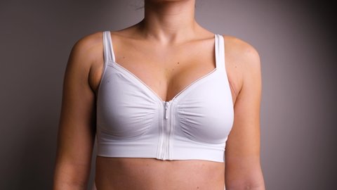 Close Up of Female Turning Around Wearing White Surgical Bra Post Breast Augmentation.