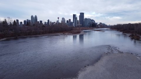High aerial reveal of downtown Calgary Alberta and the East Village over the Bow River.