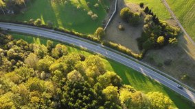 Steady aerial drone shot (vertical) of country road in scenic rural landscape at sunset 
