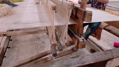Children's manual labor at a carpet factory. Anonymous boy weaves a pattern on a loom.