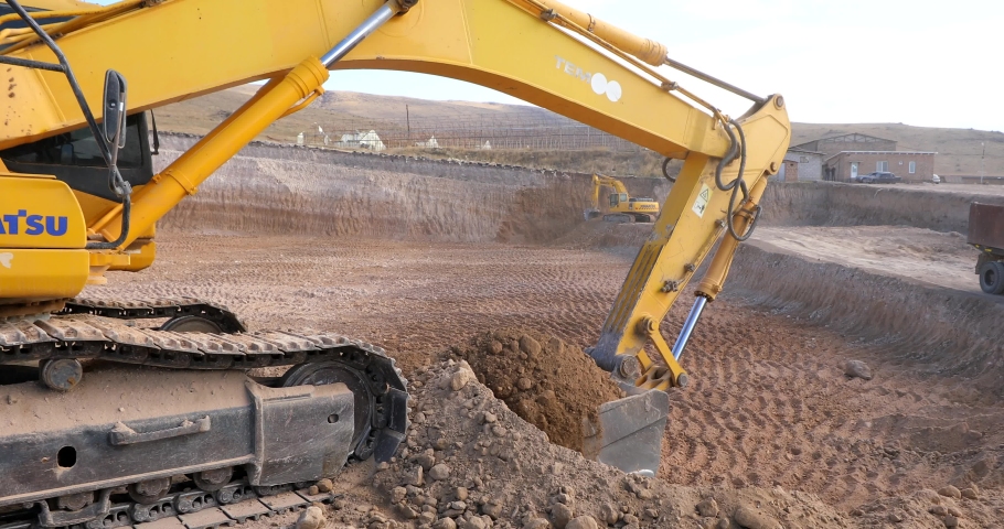 Excavator transferring a ground with a heavy bucket into the back side of the truck. | Shutterstock HD Video #1083875947
