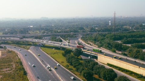 Aerial view of Indian capital and metropolitan city roads of New Delhi, India. Drone shot of 8 lane highway in Delhi. Roads of developing India. Metro rail track with highways and cityscape, India. 4K
