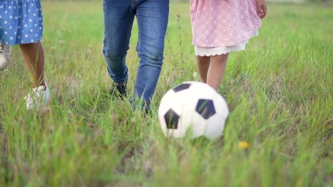 Happy family of children run across field. Group of children are playing with soccer ball. Happy family in park.Ball game in park. Family soccer game. Happy children in park run with ball.Happy family