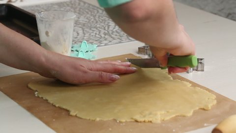 The woman cuts the rolled biscuit dough. Cooking marshmallow sandwiches. Next to it is a form for dough in the form of a snowflake. Close-up shot