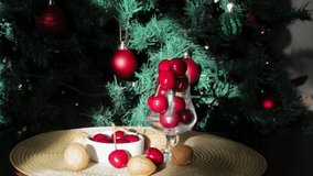 Christmas scene on video, with cherries, nuts, and a decorated Christmas tree in the background with flashing lights.