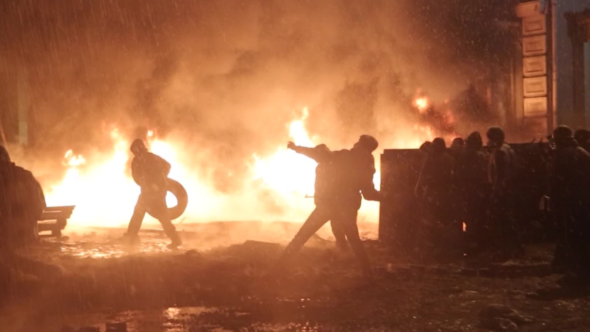 Kiev, Ukraine, 19 January 2014: A protester throws a stone into a fire on the Maidan on the street Grushevskogo January 19, 2014