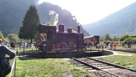 Primolano Vicenza Italy OCTOBER, 10, 2021 Group of tourist with kids watch museum show of railway workers spin turntable platform around with steam train locomotive. Railway stock technology display 