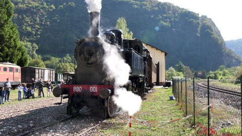 Primolano Vicenza Italy OCTOBER, 10, 2021 Restored old beautiful Steam Locomotive train stand and blow white steam in train station in Italy on display with tourist watching