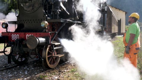 Primolano Vicenza Italy OCTOBER, 10, 2021 Static view railway staff worker by old locomotive steam train put hand on flowing steam burst form train