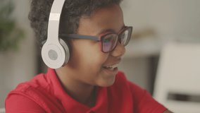 Cute black boy learning foreign language online, wearing headphones, education