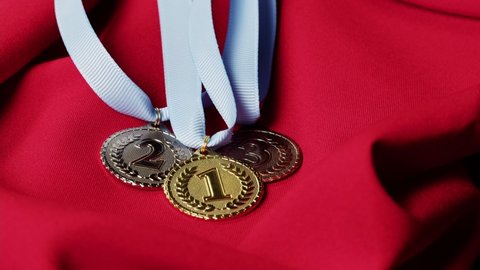 Gold, silver and bronze medals with ribbons on red background close-up. First, second and third place. Award and victory, winning the championship. 